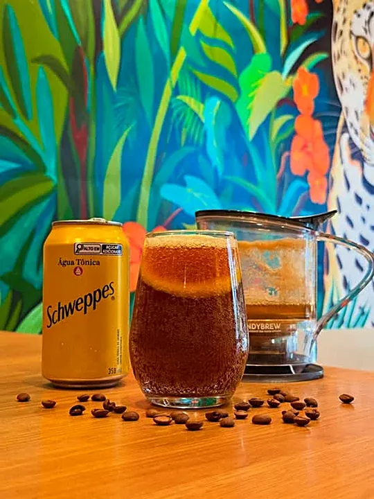 Espresso tônica sobre a mesa com o mural de folhagens ao fundo